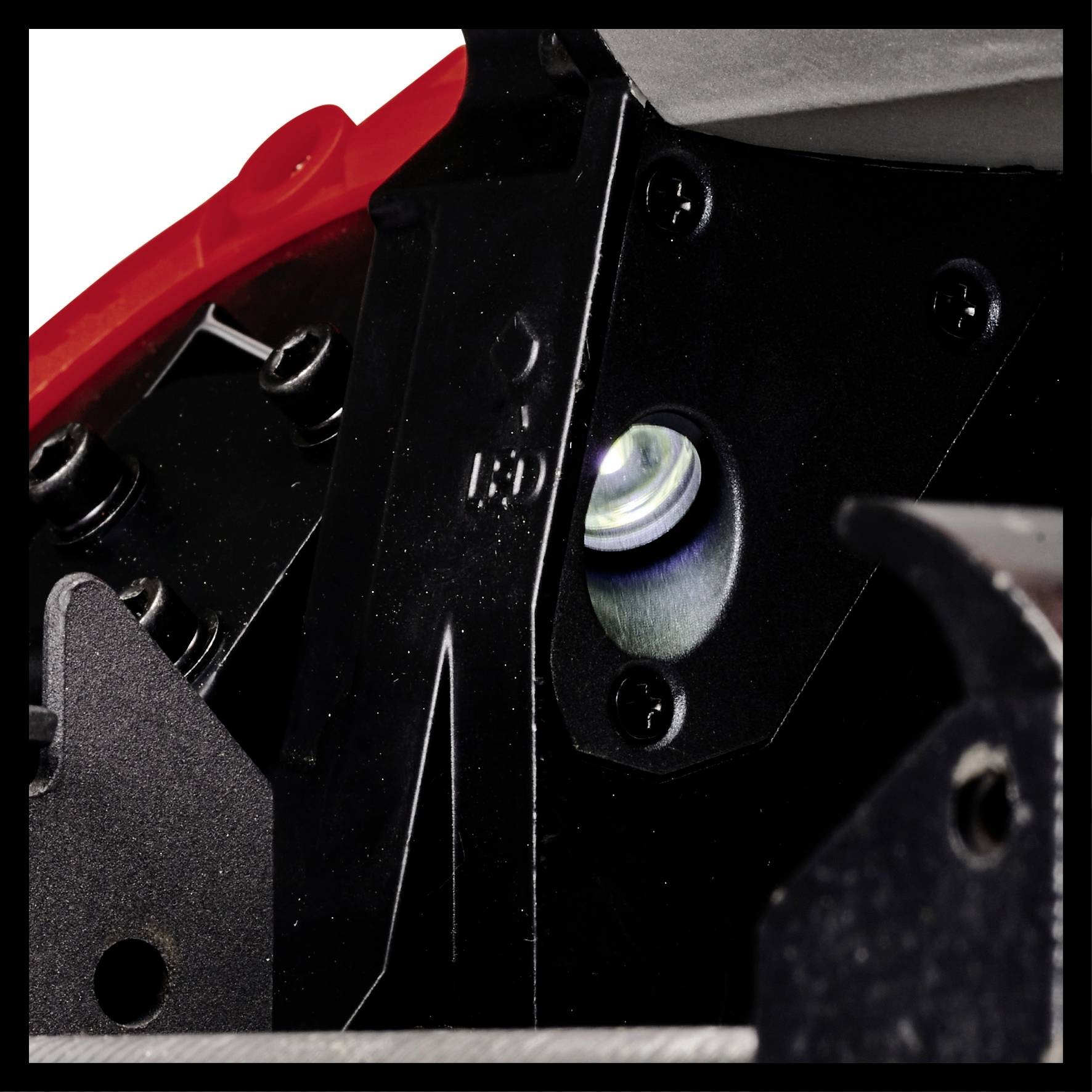 Close-up of a red and black mechanical device with shiny metal parts and screws.