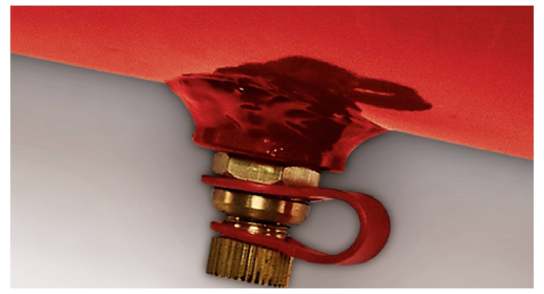 Close-up of a red fire extinguisher safety seal and pin, showing the tamper ring and valve assembly.