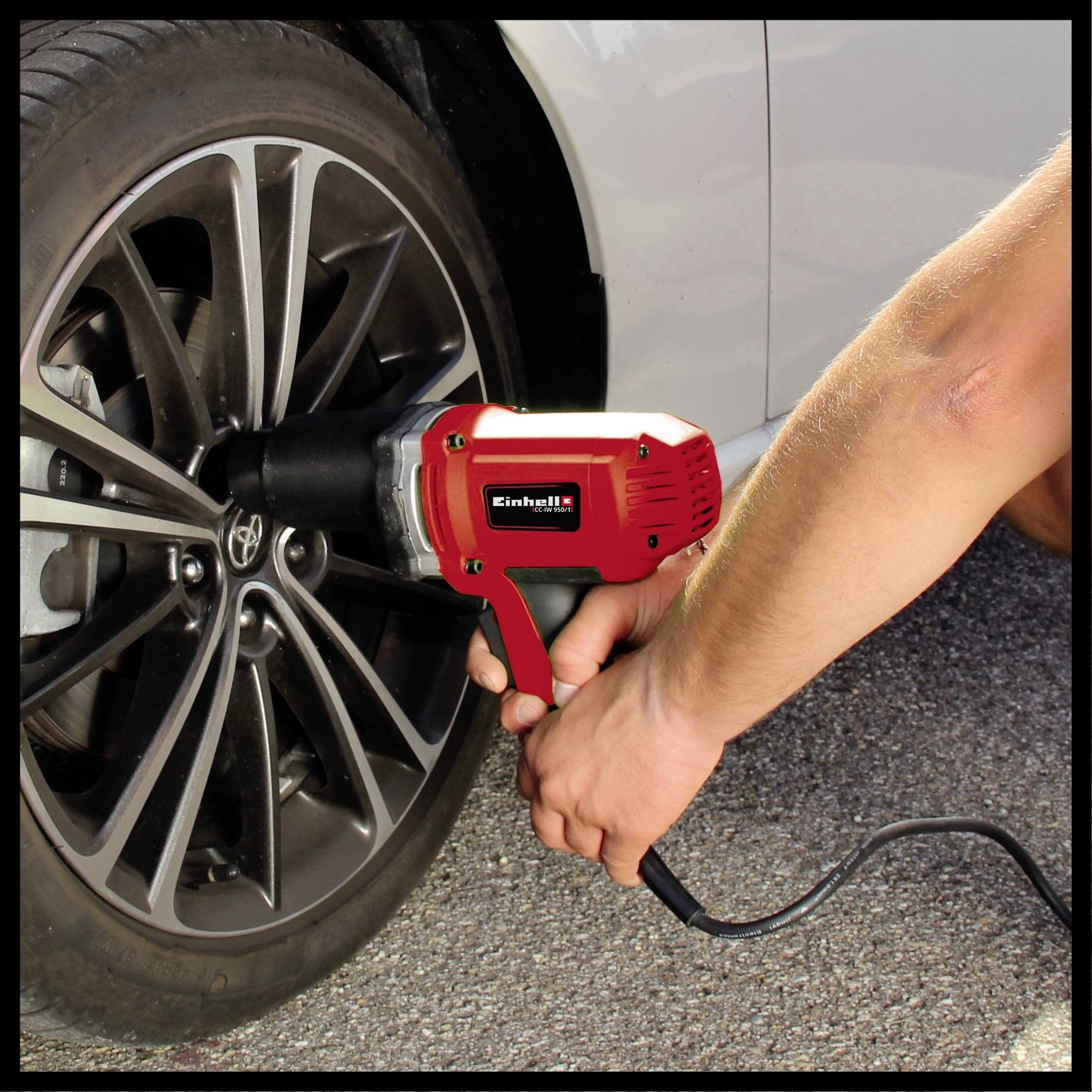 A person is using an electric impact wrench to secure the wheel nuts of a car.