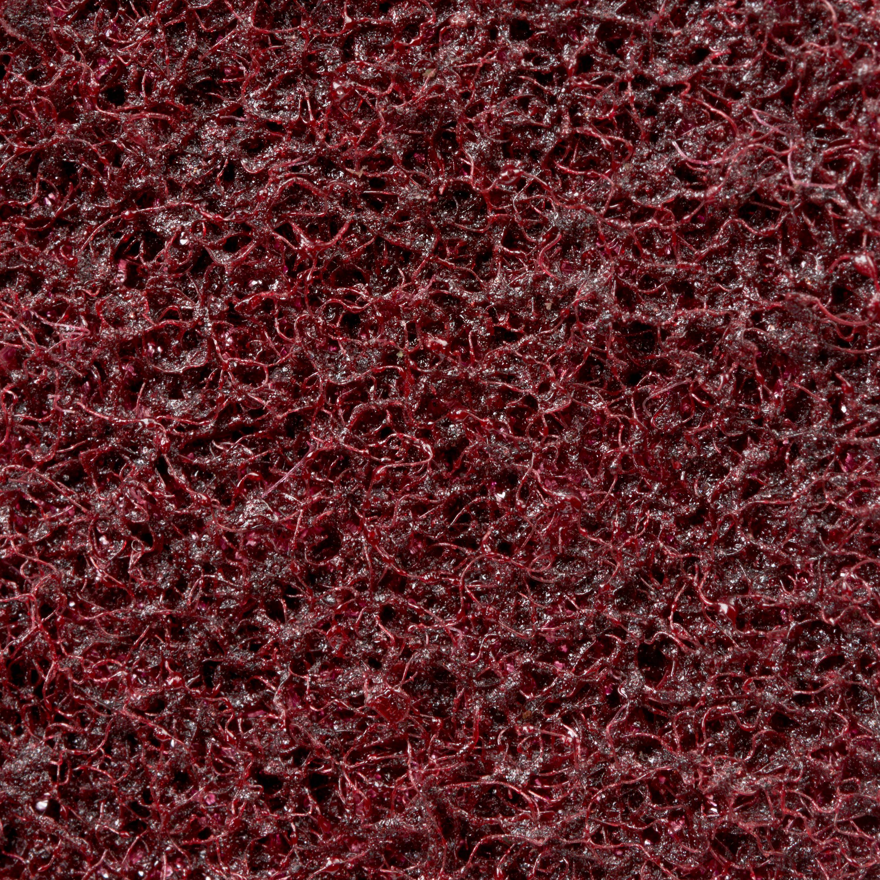 Close-up of a dark red abrasive surface with a chaotic texture of intertwined fibres.