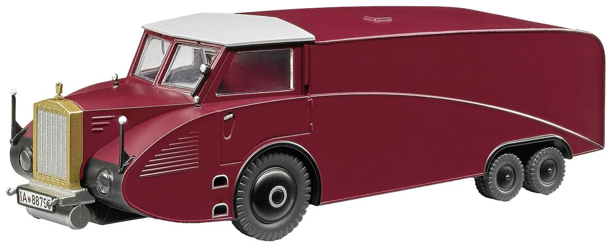 A red, vintage lorry model with a curved design and three axles, parked on a flat surface, photographed from the side.