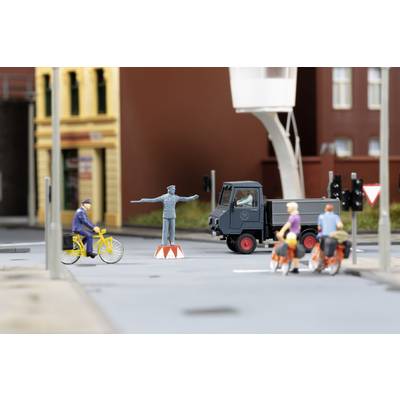 A miniature scene depicts a city with a lorry, a policeman on a plinth, cyclists and pedestrians.