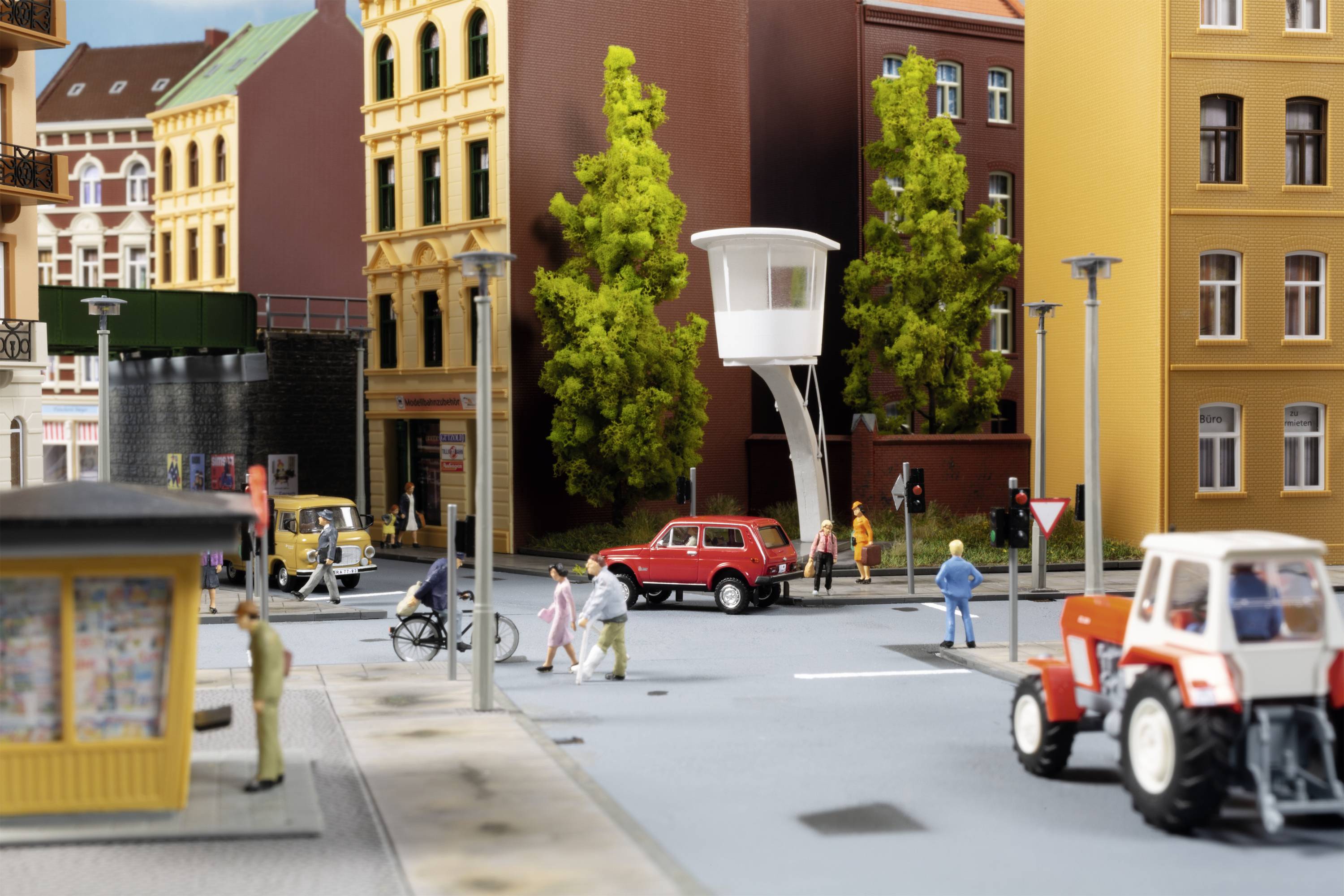 A detailed urban model featuring cars, bicycles, and pedestrians at a junction. Multi-storey buildings and trees in the background.