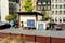 A miniature scene depicts a small warehouse on a cobbled square with model vehicles and adjacent buildings. Two people are standing outside.