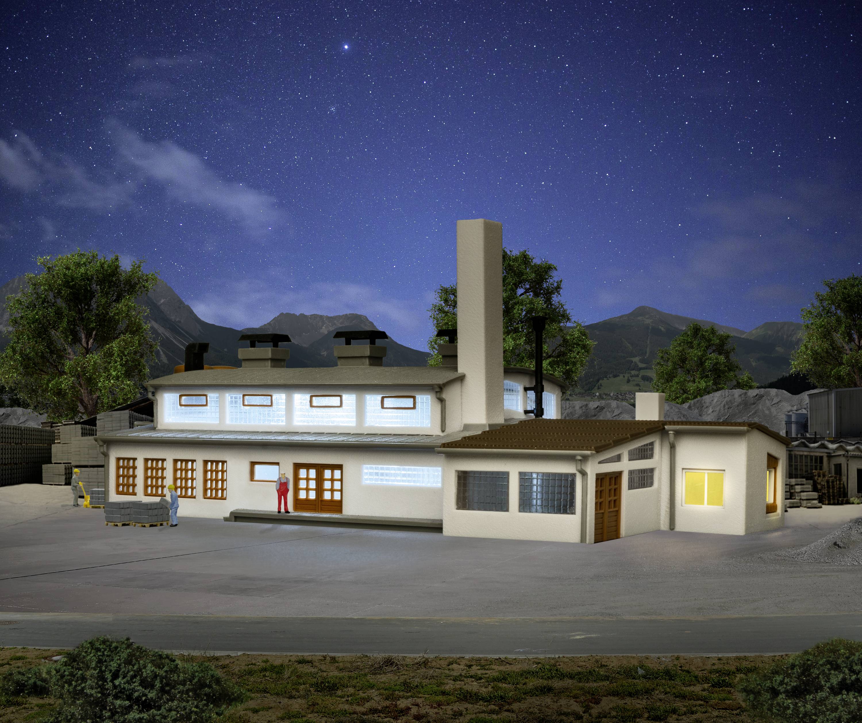 A lit building with a chimney, surrounded by trees and mountains, beneath a starry night sky.