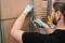 A person is wearing gloves and cutting a parcel tape with a tool from a cardboard box.