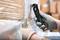 A hand wearing a grey glove holds a black safety knife and cuts through packaging film covering cardboard boxes.