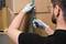 A person wearing gloves is opening a package wrapped with a blue ribbon using a craft knife.