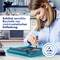 A woman in blue workwear is working with a tool on an electronic device. A sign emphasises protection against electrostatic discharge.
