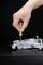 A hand is repairing a drone with a screwdriver. The drone is lying flat on a dark surface.