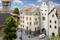 Miniature town with historic buildings, archway with clock, a car and people on a cobbled street, trees in the background.