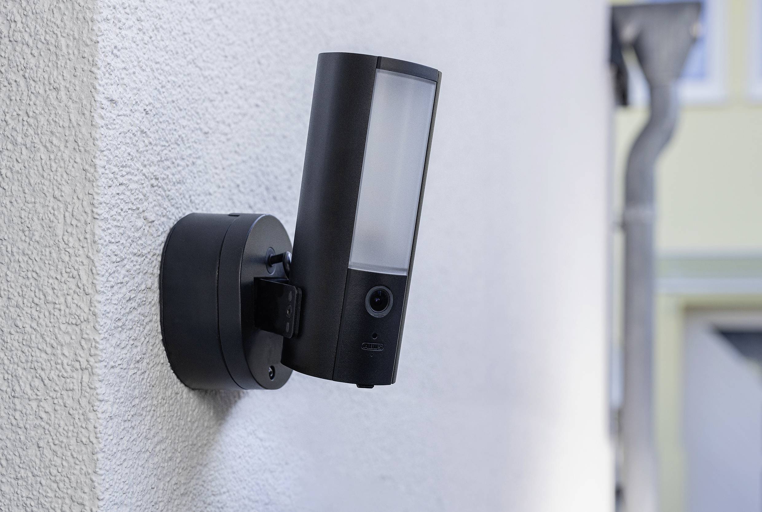 External camera with motion sensor mounted on a wall. It has a sleek, modern design and is intended for surveillance.