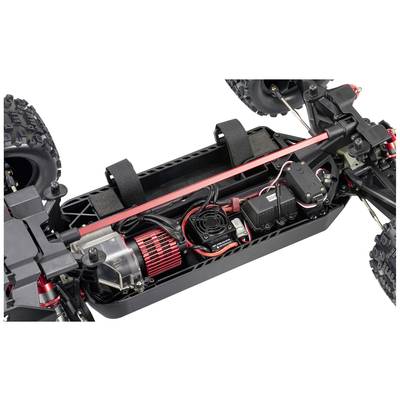 Remote-controlled car chassis in close-up. The motor, wiring, battery housing, and suspension components are visible.