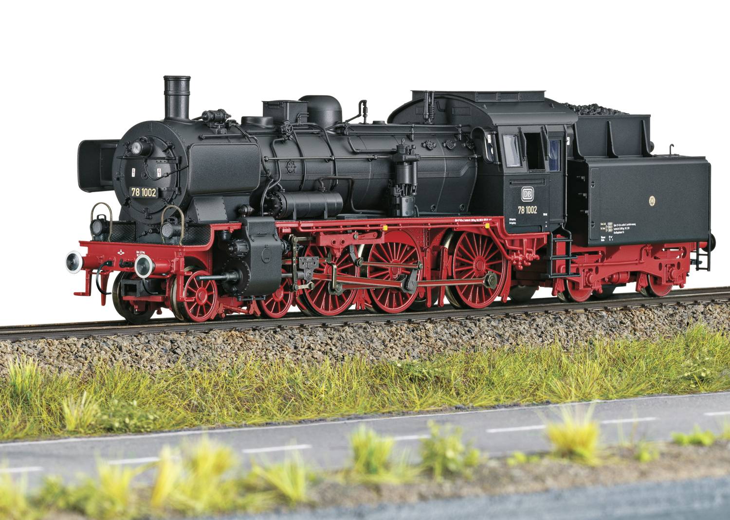 Black steam locomotive with red details and wheels travelling on railway tracks. The locomotive demonstrates historical engineering and design.