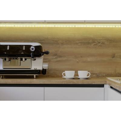 A coffee machine on a worktop beside two empty mugs, surrounded by warm ambient lighting.