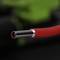 Close-up of a red cable with exposed copper wires, focused against a blurred background.