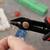'Close-up of a hand gripping a red pair of pliers and cutting a resistor. Blurred electronic accessories in the background.'