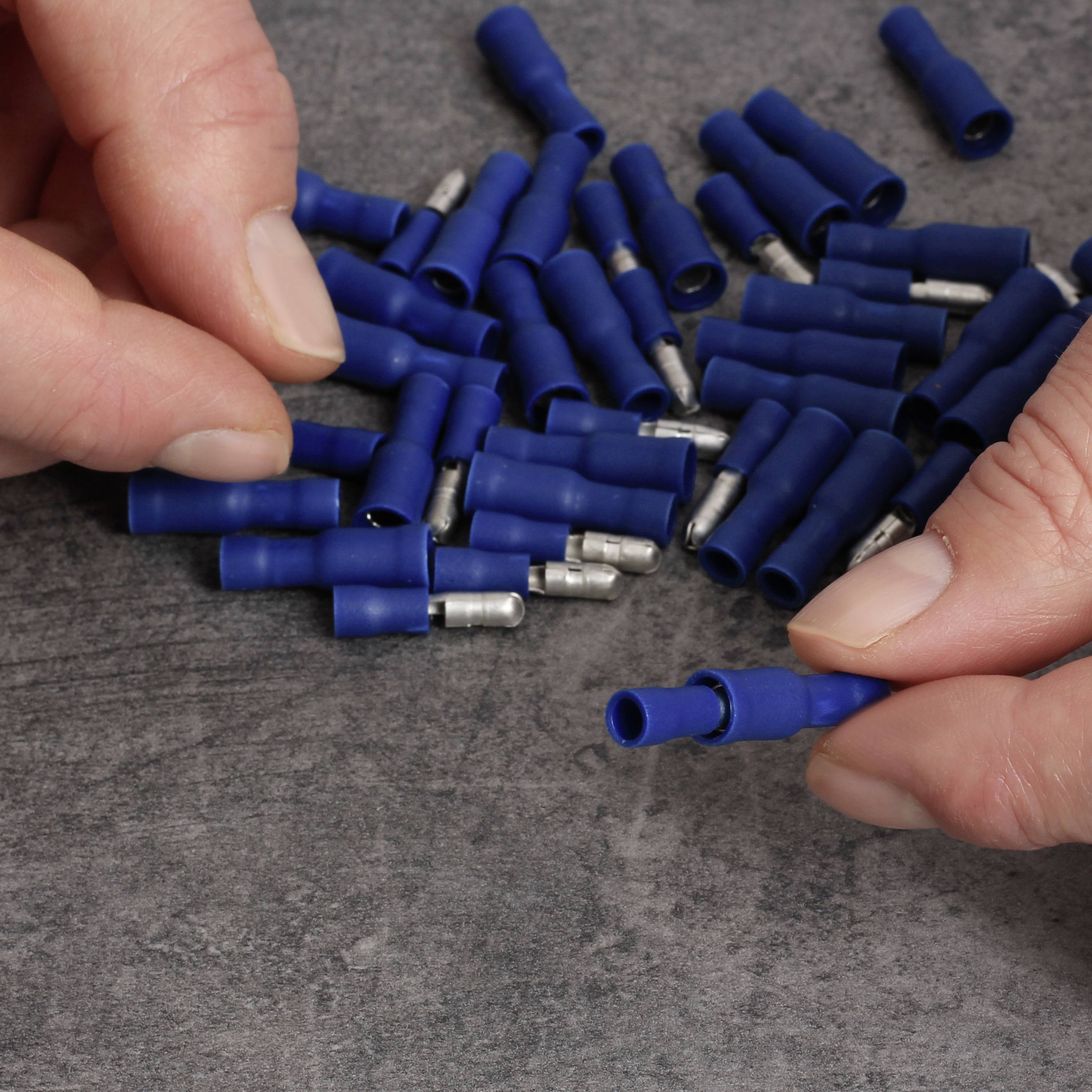 Two hands are holding blue cable connectors on a table. The background shows additional similar connectors.