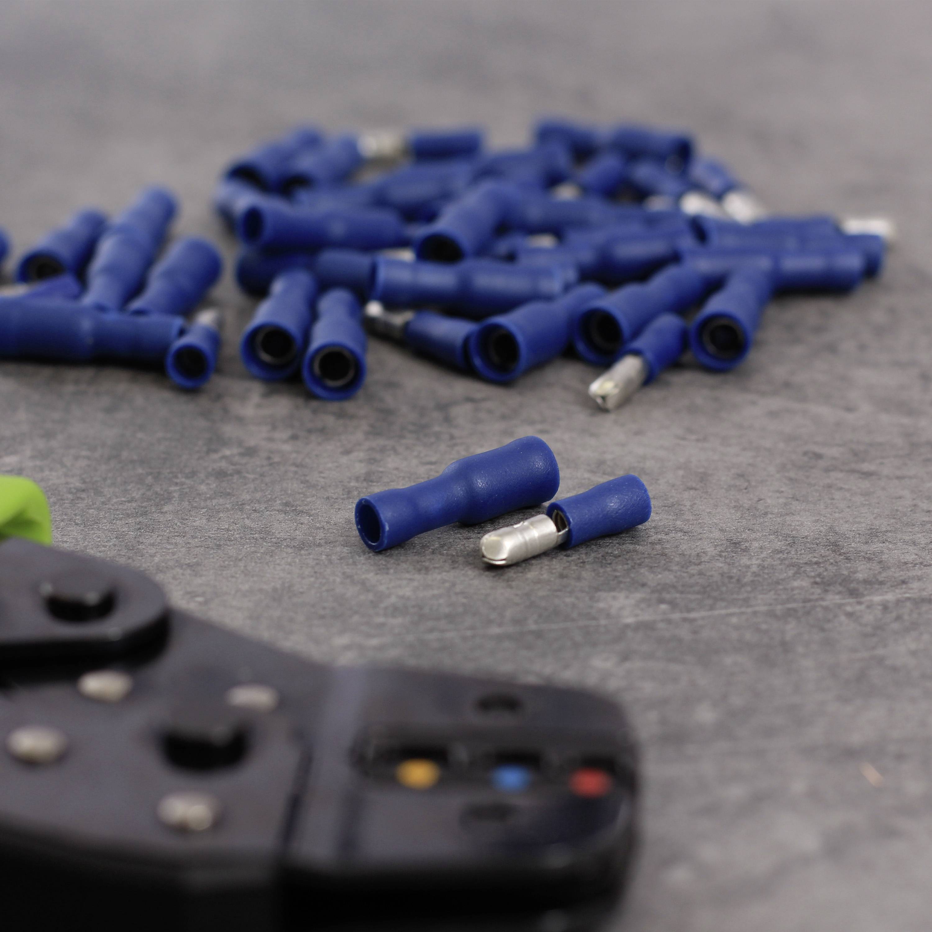 Blue cable connector and crimping pliers on a grey background. Several connectors are scattered, with one connector and pliers in the foreground.