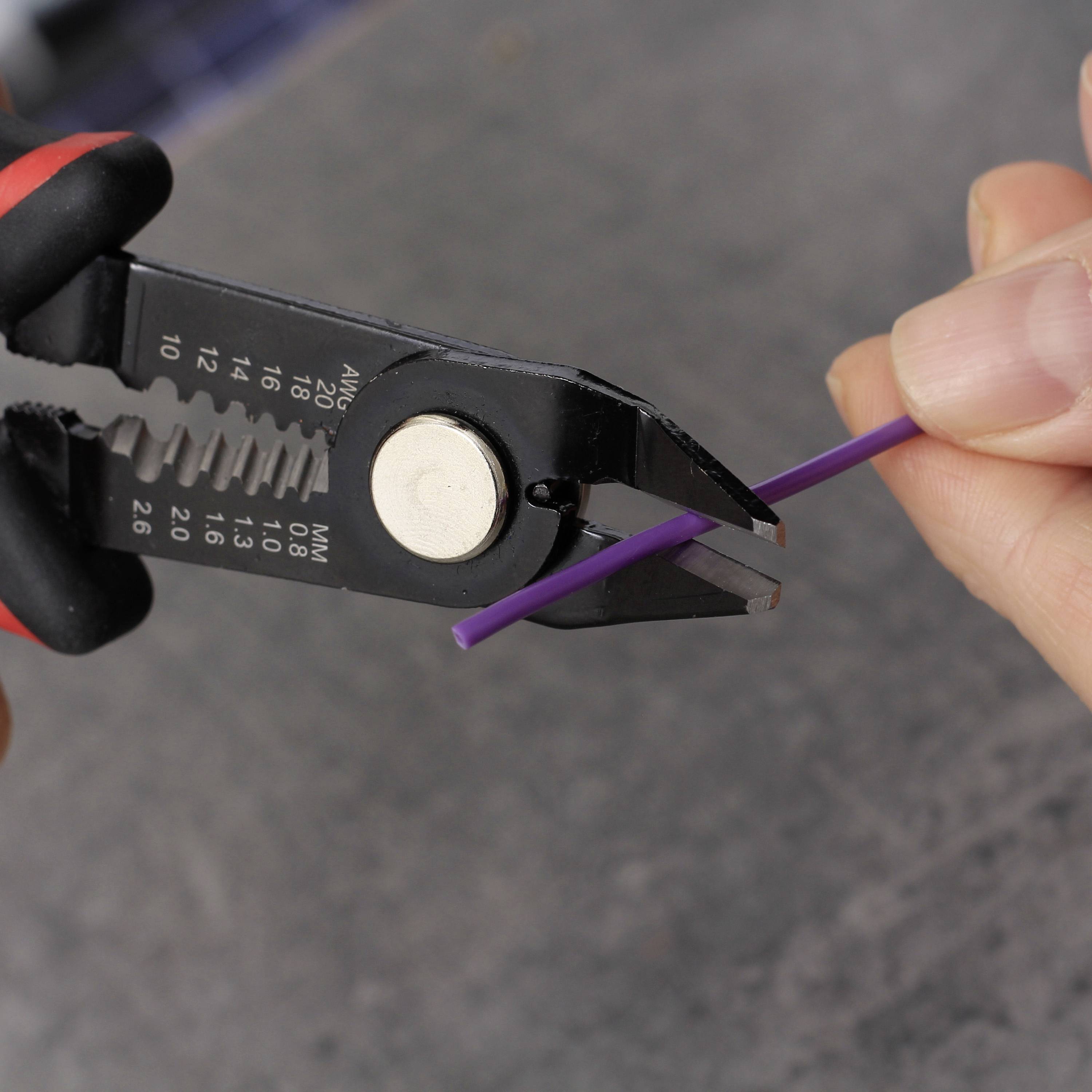 A hand is holding wire cutters, cutting a purple wire. The background is blurred, with the focus on the tool and wire.