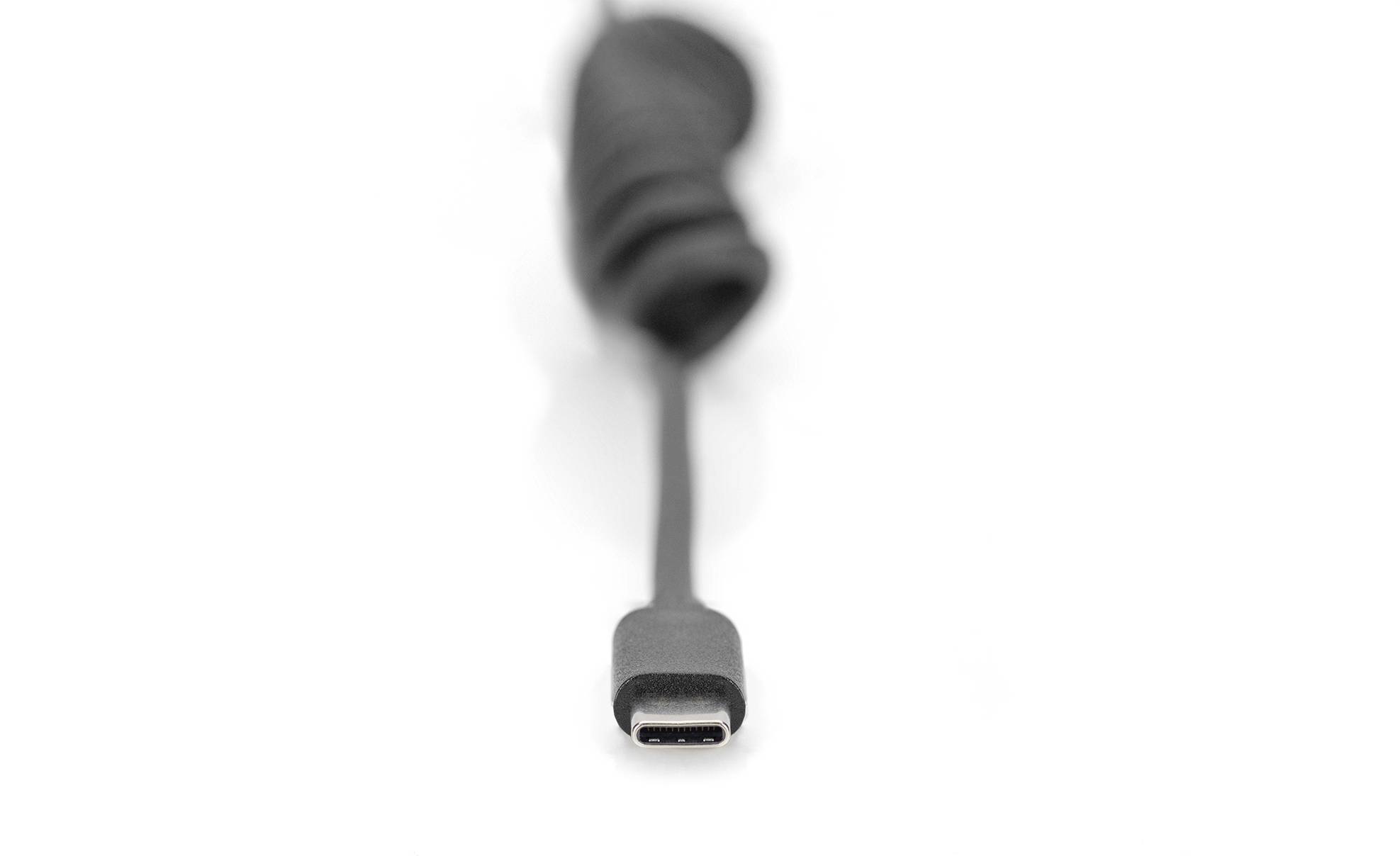 A black USB-C cable, focused on the connector pointing forwards. The background is blurred.