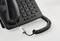 Black, corded office telephone with numeric keypad and handset resting on the base. The cable is coiled in a spiral shape.
