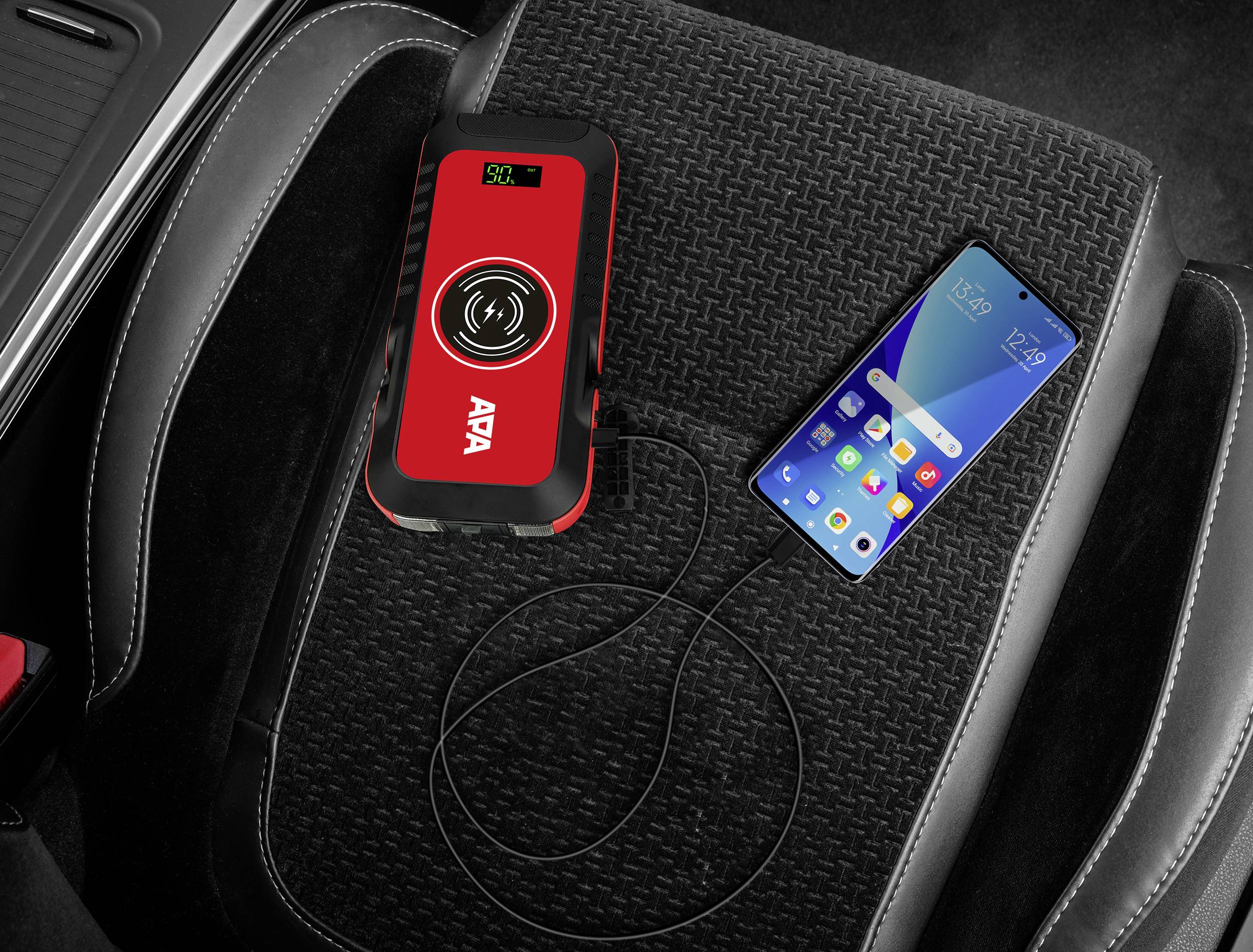 Portable charger on a car seat, connected to a mobile phone. Charger shows green light, mobile phone is charging.