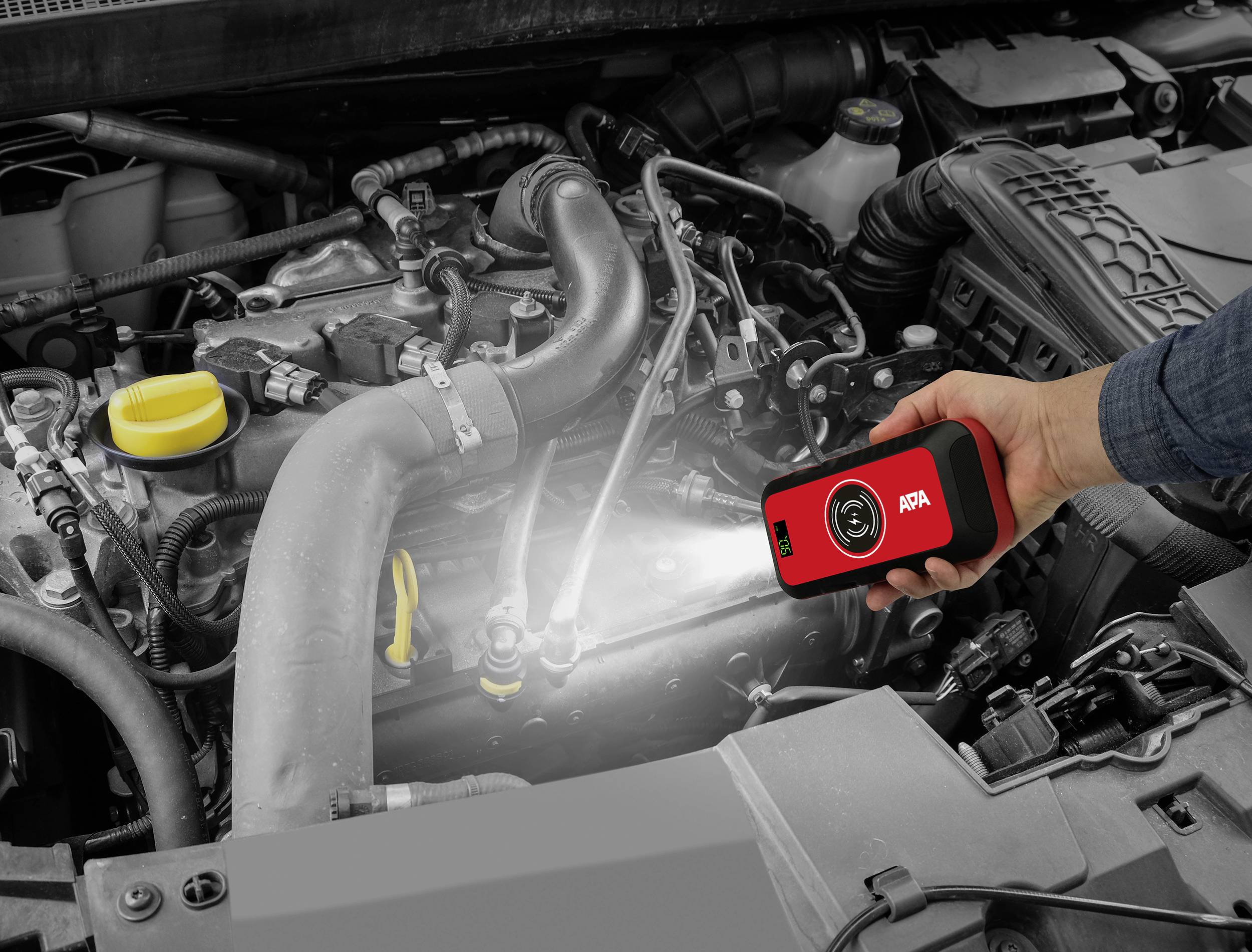 Someone is examining a car engine with a portable diagnostic device that lights up and illuminates the engine.