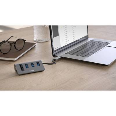 Laptop on a table, connected to a USB hub. Next to it, a pair of glasses and a glass of water.