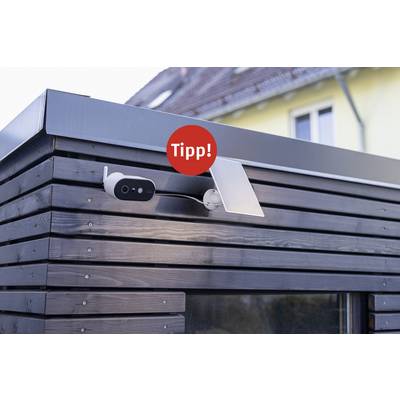 A security camera is mounted on a wooden wall of a building. Above the camera is a red circle with 'Tipp!'.