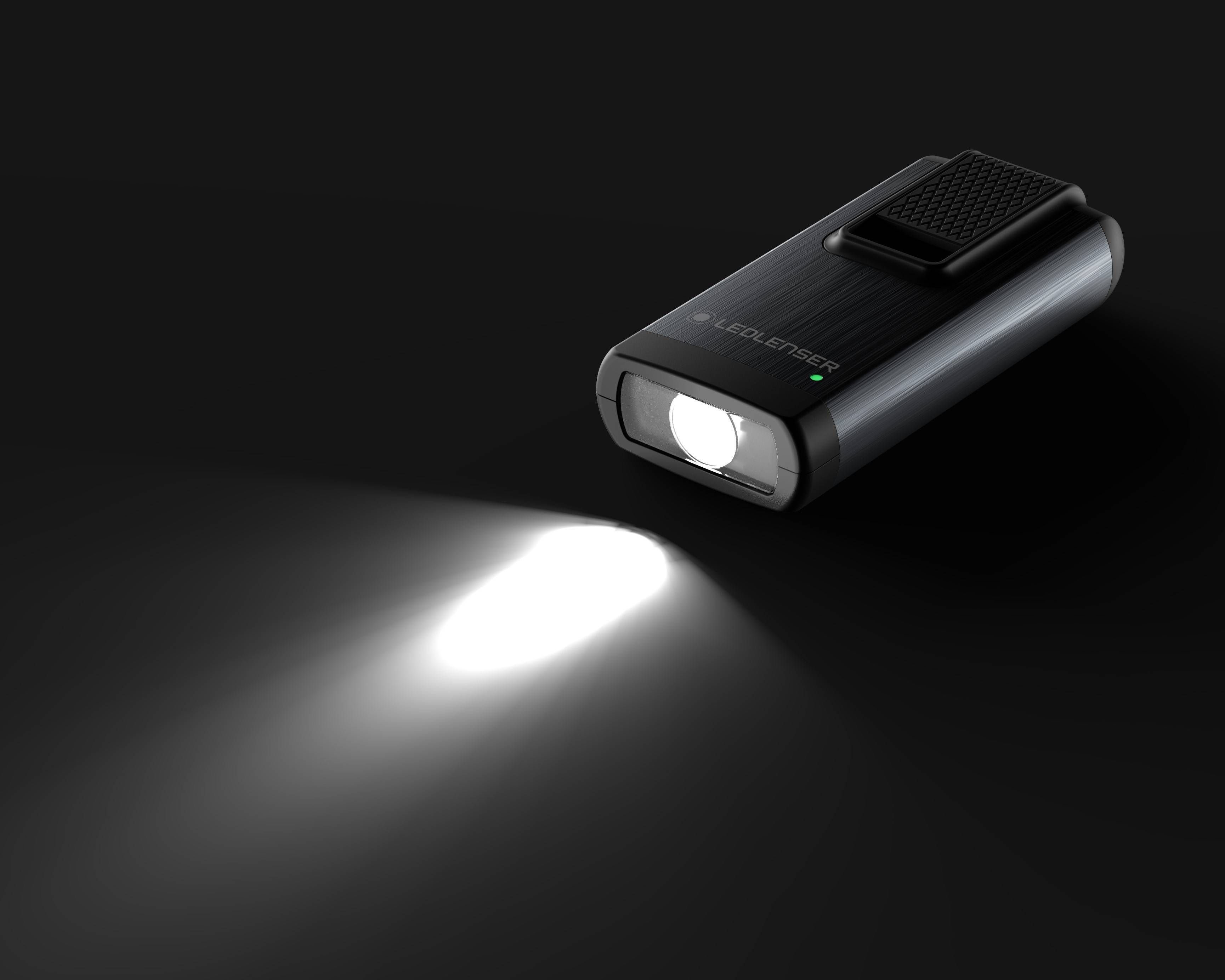 Torch illuminates against a dark background. It has a compact design and emits a powerful beam of light.