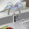 A stylish tap with multiple curved spouts is shown in action above a kitchen sink, surrounded by fresh ingredients.