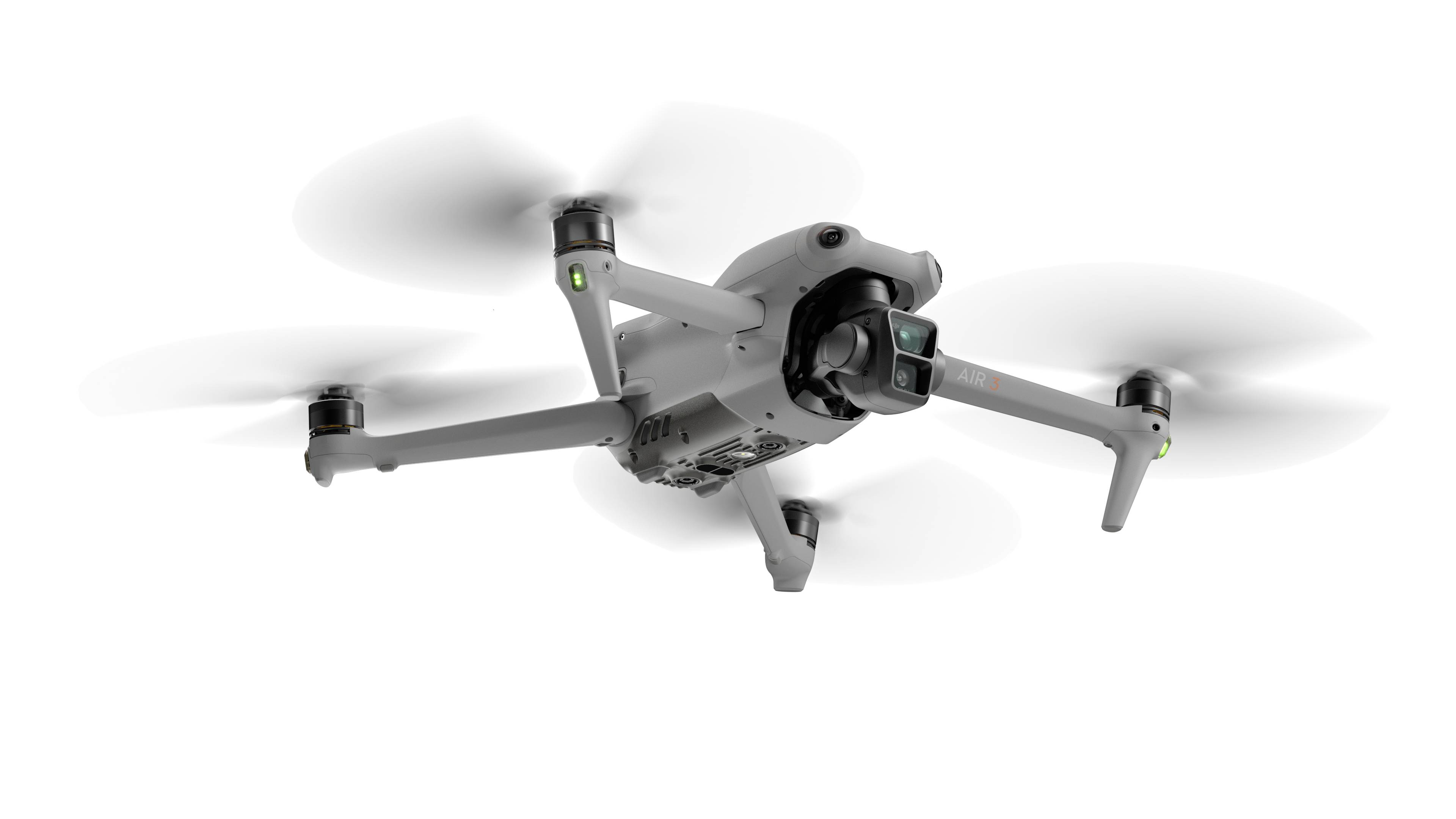 A white quadcopter drone is flying in the air. It has a camera on the front for aerial photography and surveillance.