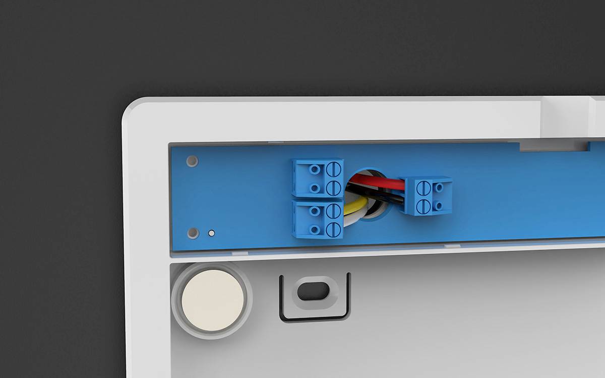 Close-up of a wall-mounting bracket with visible blue cable connections and a round magnet in the bottom left.