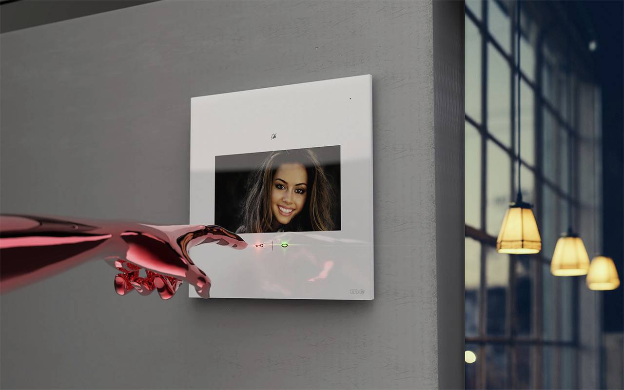 A red robotic arm touches a screen on the wall, displaying an image of a smiling woman. Lamps are visible in the background.