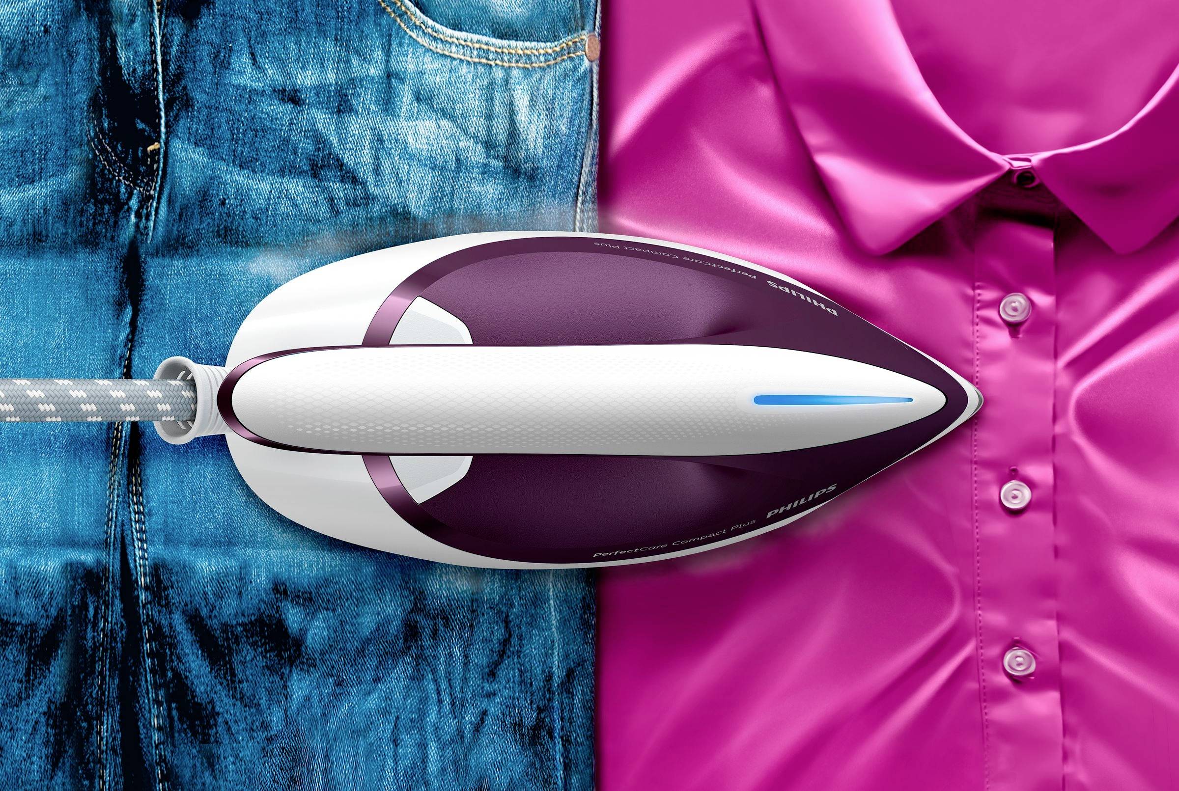 An iron glides over jeans and a pink shirt, demonstrating its ironing function on different fabrics.