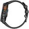Black, rugged smartwatch from the side, with orange detail. Strap and side buttons visible. Suitable for outdoor activities.