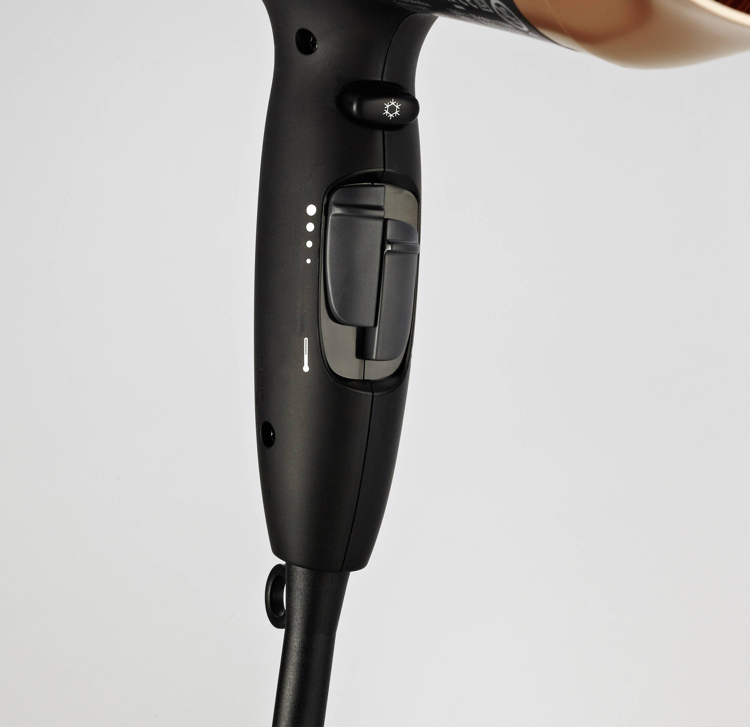 Black hair dryer with copper nozzle; visible control buttons for temperature setting and blower intensity.