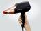 A hairdryer is being held in one hand, featuring a black and gold design. The brand name 'Panasonic' is visible.