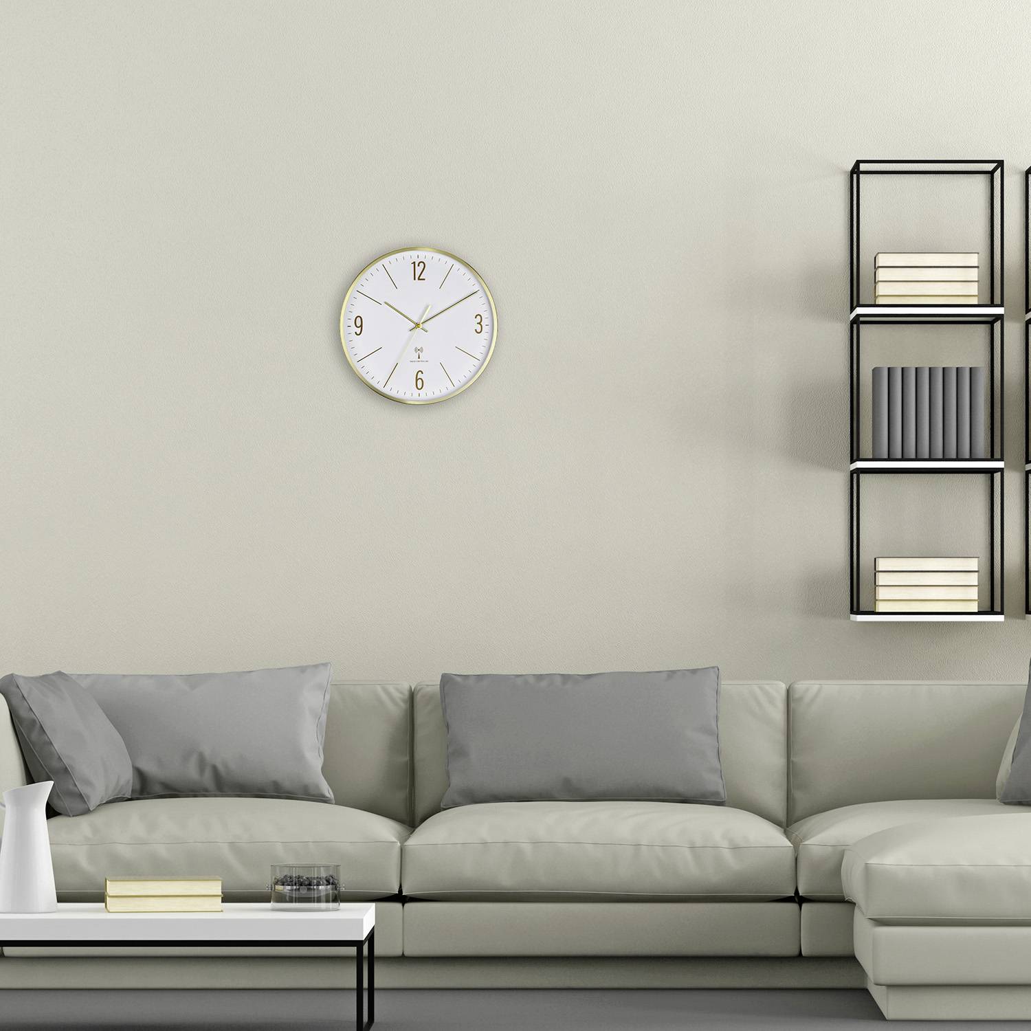 Living room with a grey sofa, white cushions, white table, decorative wall clock and bookshelf with books.
