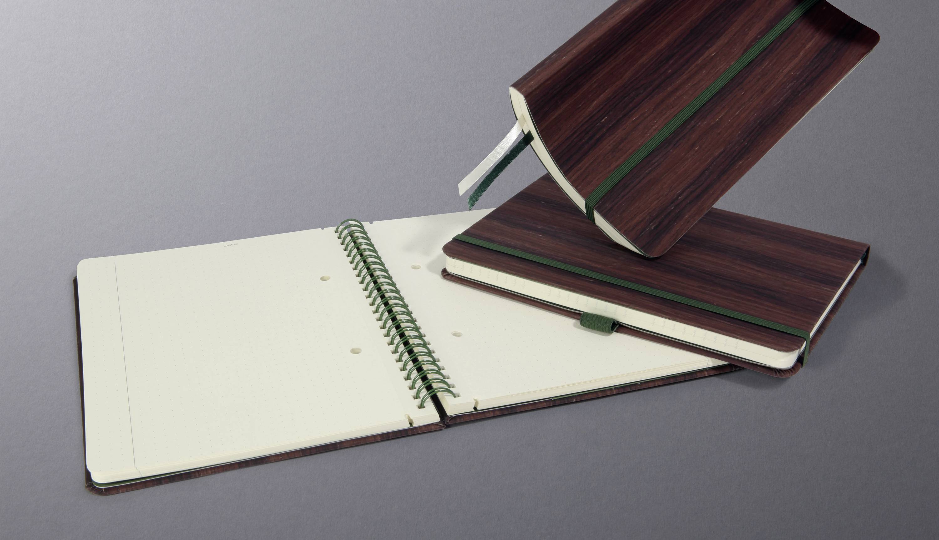 Three notebooks on a grey background. One is open, the second is closed, and the third is being held open. All have a brown cover.