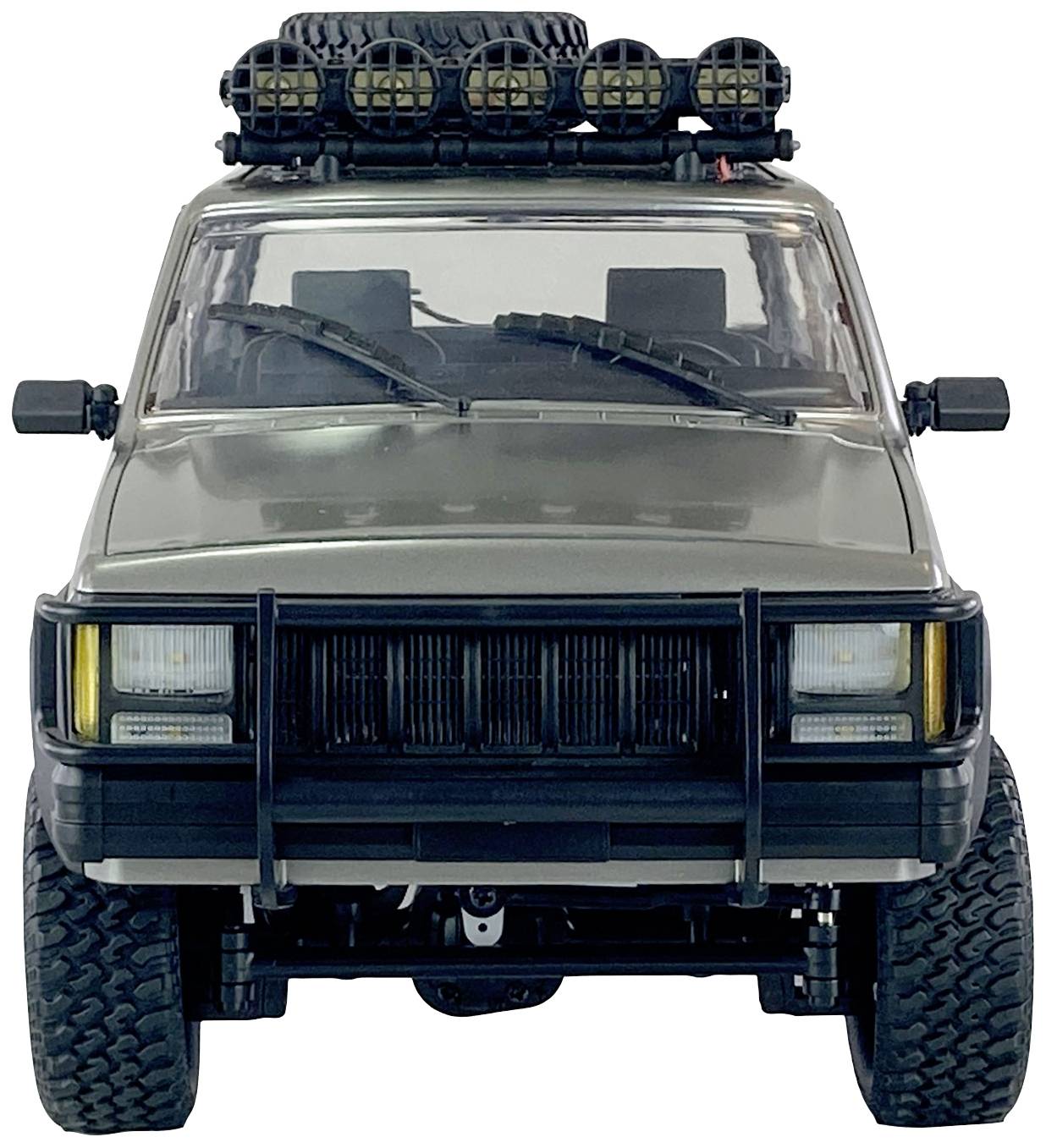 Off-road vehicle viewed from the front with large tyres, a bull bar, additional headlamps mounted on the roof, and a spare wheel.
