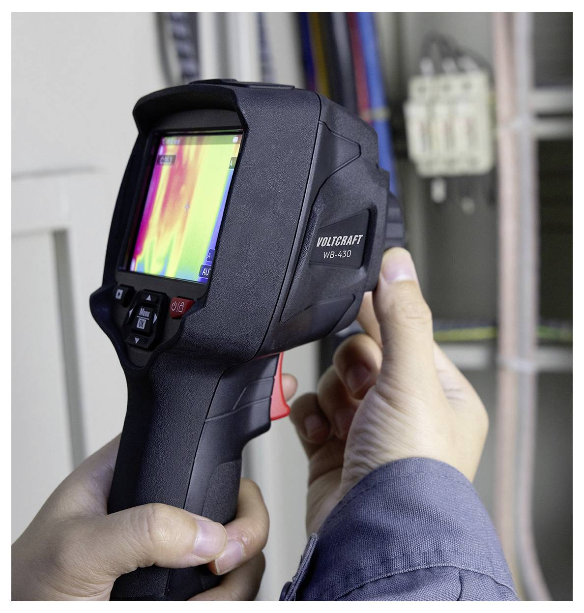 Person using a handheld thermal imaging camera to inspect electrical wiring inside a wall or panel.