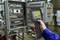 A person is measuring the temperature of electrical control cabinets in an industrial environment using a handheld thermal scanner.