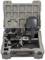 A portable thermal imaging device in an open case with accessories such as a charger and international plug adapters.