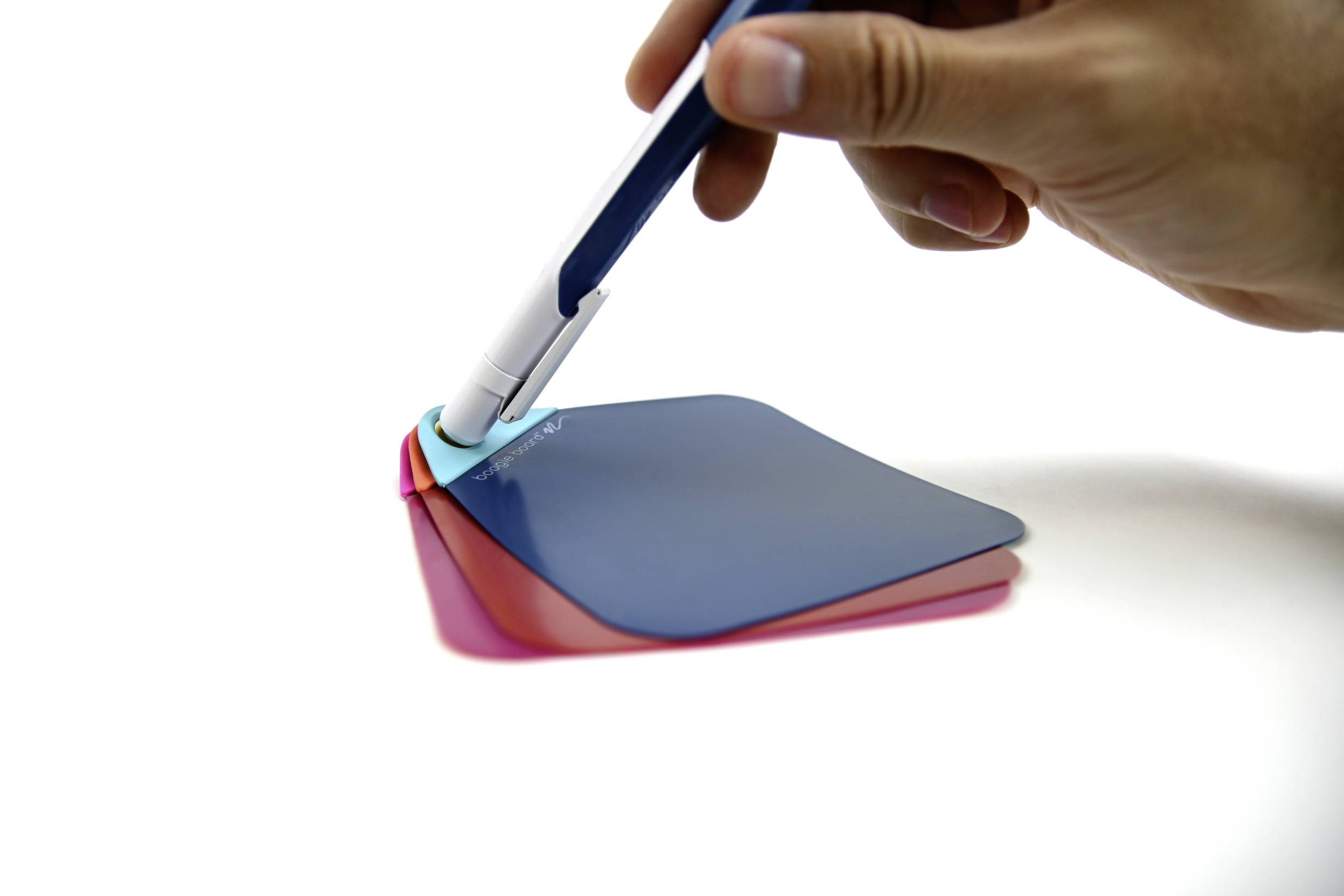 A hand is holding a pen and pointing at three overlapping, differently coloured transparent sheets on a white surface.