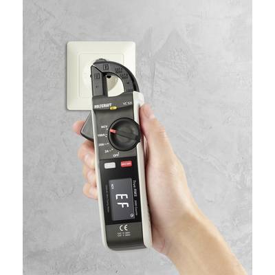 A hand holds a voltage meter in front of a socket to check electrical properties.