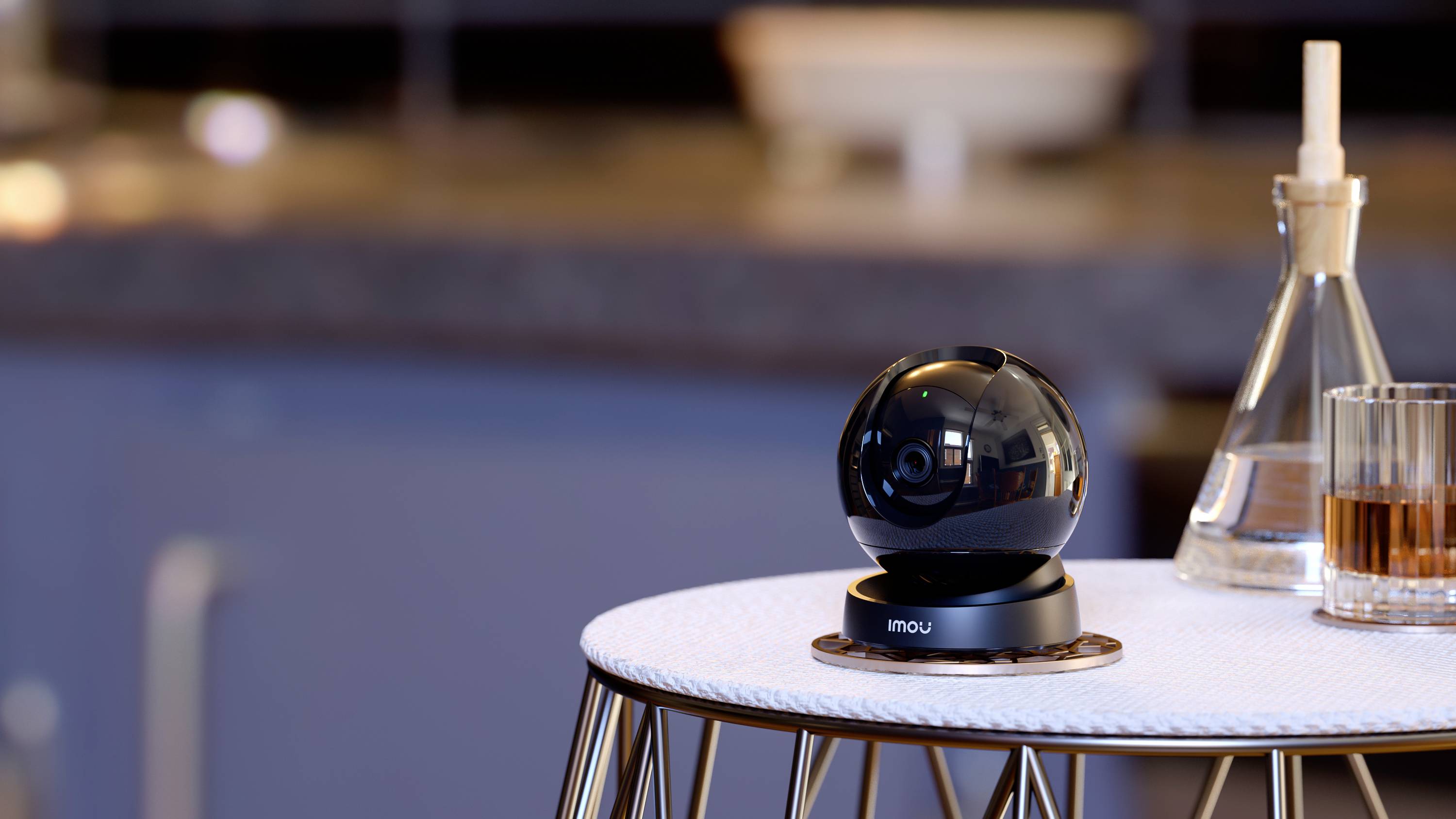 A black, round security camera sits on a table in a modern room. It is mounted on a silver stand.