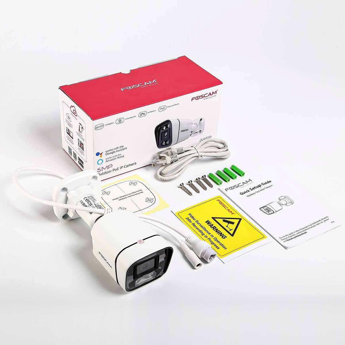 A surveillance camera with packaging and accessories, including cables, screws, and instructions placed on a table.