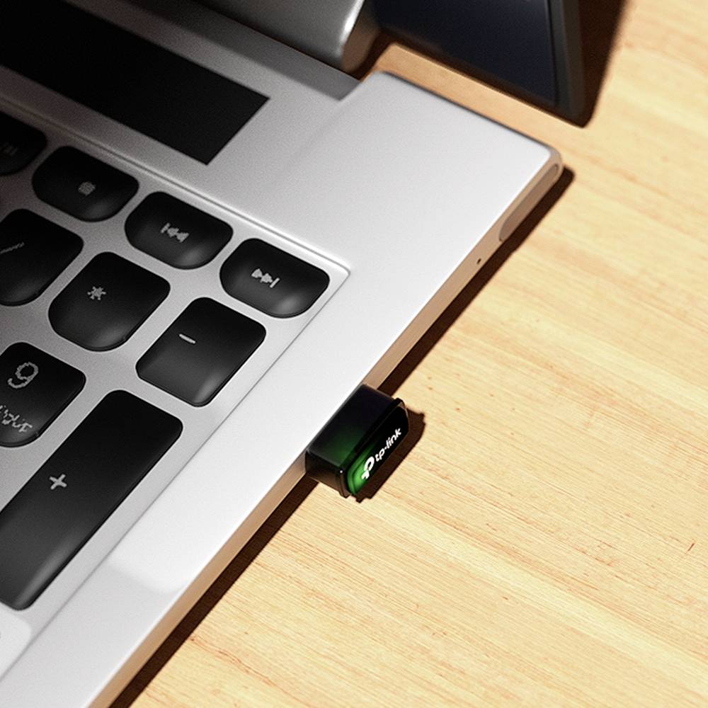 A USB stick is plugged into a laptop, which is sitting on a wooden table. The USB stick is glowing green and displays 'Lexar'.